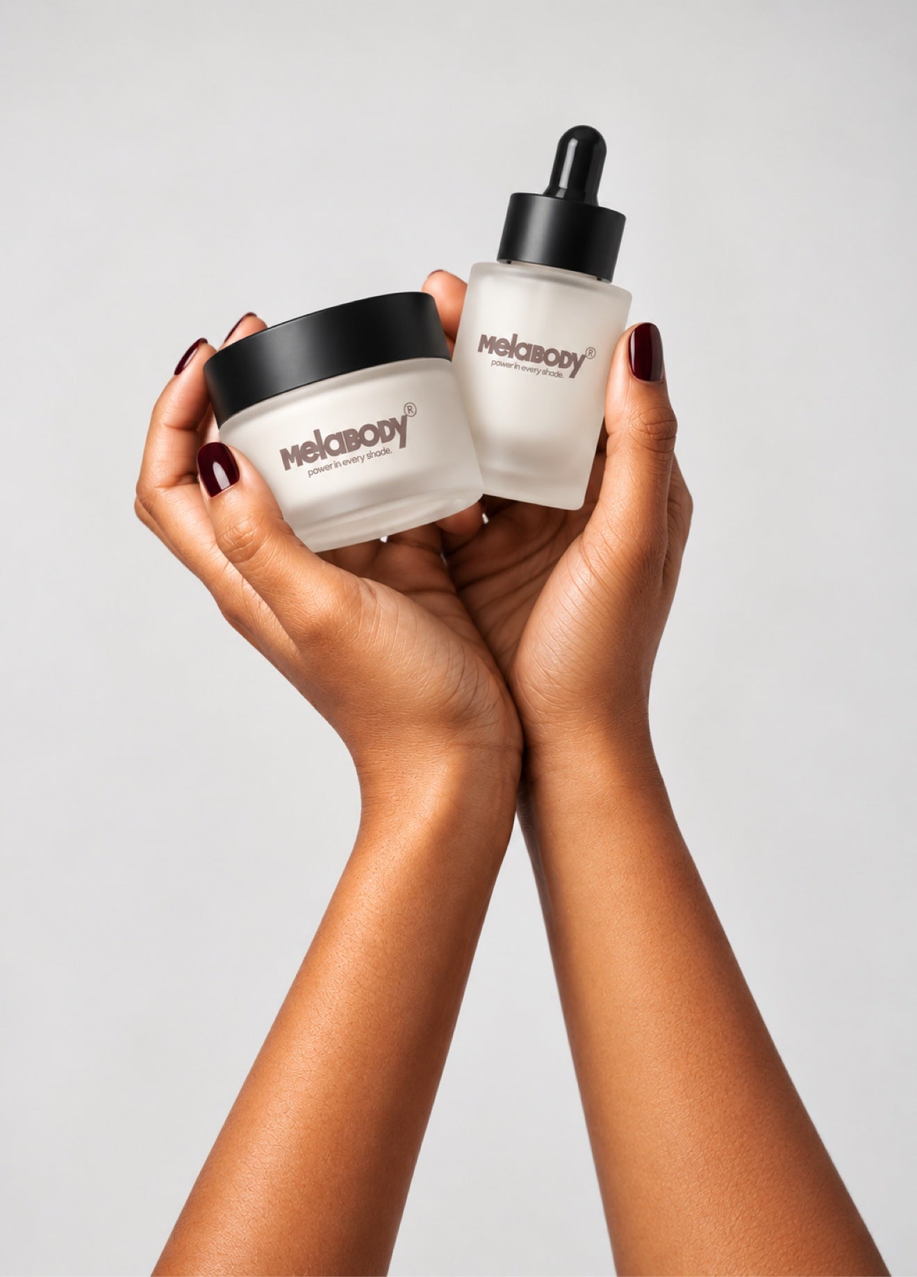 Hands holding the MelaBODY Face Serum bottle and Face Cream jar together